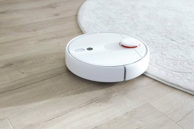 Beyaz robot elektrik süpürgesi yerde. Modern akıllı aygıt temizleme tabanı.