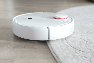 Beyaz robot elektrik süpürgesi yerde. Modern akıllı aygıt temizleme tabanı.