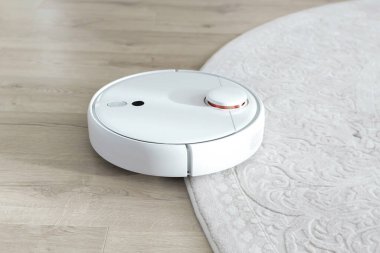 Beyaz robot elektrik süpürgesi yerde. Modern akıllı aygıt temizleme tabanı.