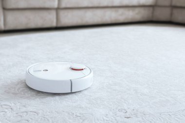 Halıdaki beyaz robot süpürgesi. Modern akıllı aygıt temizleme tabanı.