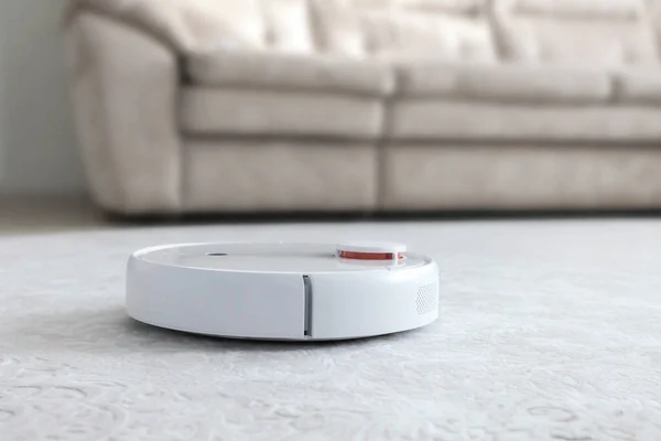 地毯上的白色机器人吸尘器 现代智能设备清洗地板 — 图库照片