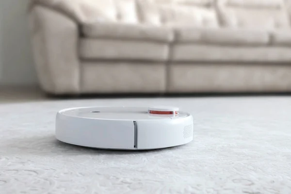 Halıdaki beyaz robot süpürgesi. Modern akıllı aygıt temizleme tabanı.