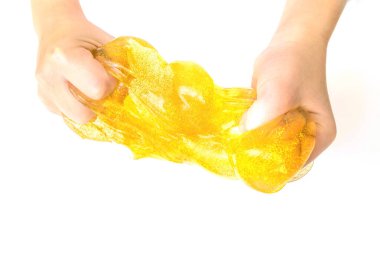 Modern toy called slime. Child playing transparent yellow slime. Hands holding a mucus isolated on a white background. Selective focus. clipart