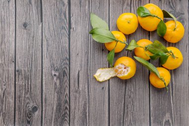 Olgun portakallı taze mandalinalar ve kırsal bir arka planda yeşil yapraklar. Düz yatıyordu. Üst Manzara. Boşluğu kopyala.