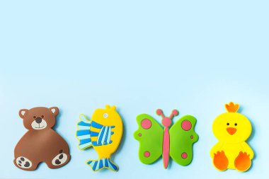 Renkli lastik banyo oyuncakları: Ayı, balık, ördek, mavi arka planda izole edilmiş kelebek. Üst görünüm, düz görünüm, kopyalama alanı.