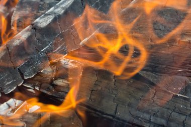 Yakacak odunların yakın plan fotoğrafı, siyah yanmış odun ve turuncu alev.