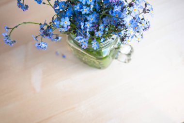 Odaklanmamış bir arka planda, cam bardaktaki çiçekleri unutma.