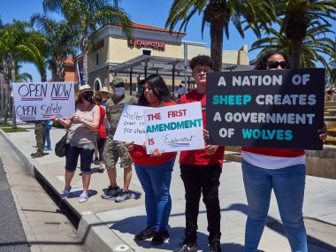 SANTA ANA, Kaliforniya / ABD - 24 Nisan 2020: Kapatma karşıtı protestocular ve aileleri Kaliforniya 'daki ev düzenine karşı bir sokak köşesinde toplandılar.