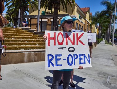 SANTA ANA, California / USA - April 24, 2020: Anti-shutdown protesters and their families gather at a street corner against the stay at home order in California. clipart