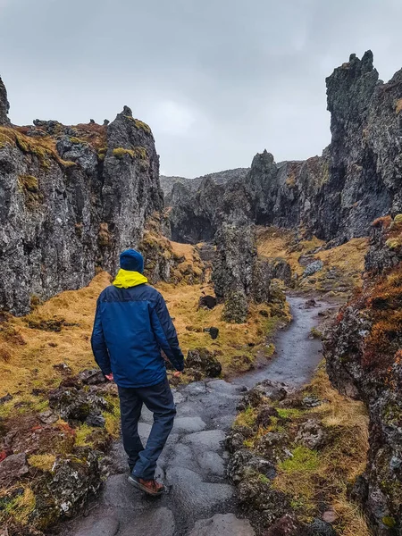 man walking down a path between volcanic mountains in Iceland with dramatic colors