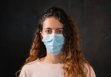 Coronavirus. Koronavirüse karşı koruma maskesi takan genç bir kadın..