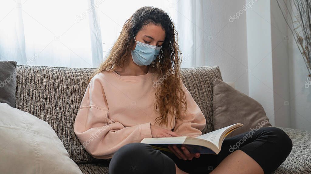 Coronavirus.Teenager reading a book at home, protected against the coronavirus. Pandemic. Social distance
