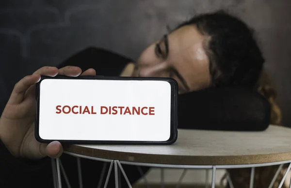 Social distance. Young woman resting while holding a mobile phone with a blank screen to put a text message or advertising content, with a vintage background room. Social distance. Coronavirus devices. Social distancing. Protection against pandemics