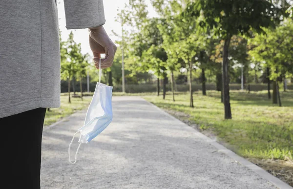 Sosyal mesafe. Elinde koruyucu bir maskeyle parkta yürüyen bekar bir kadın. Coronavirus salgınını sona erdiriyorum. Coronavirus cihazları. Sosyal uzaklık. Salgınlara karşı koruma