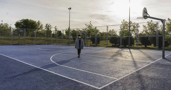 Social distance. Single woman walking around a basketball court maintaining social distance in a state of alarm because of the coronavirus. Coronavirus devices. Social distancing. Protection against pandemics