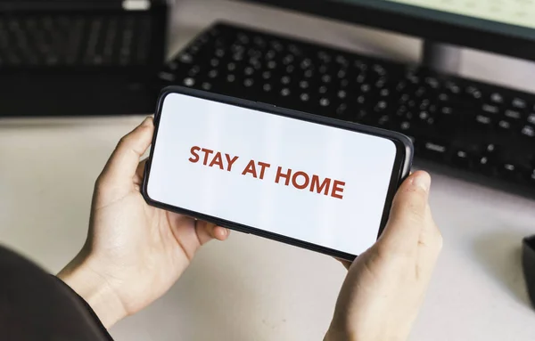 Stay at home. Put your message on the phone. Hands of a woman holding a mobile phone with a blank screen to put a text message or advertising content. Social distance. Coronavirus devices. Social distancing. Protection against pandemics