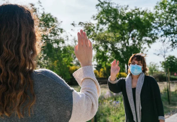 Sosyal mesafe. İki kadın güvenli bir mesafede birbirlerini selamlıyorlar. Salgın. Coronavirus cihazları. Coronavirus. Covid 19.