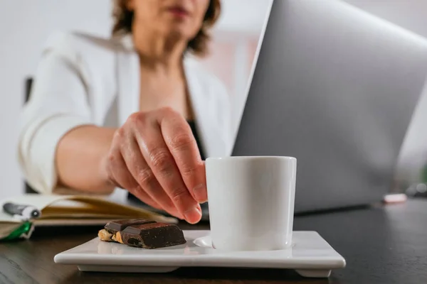 Businesswoman having coffee while she works. Senior woman working from home. Having a coffee. Coffee break.