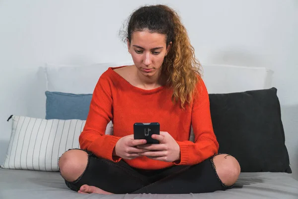Oturma odasındaki akıllı telefonu kullanan bir genç. Akıllı telefonu kullanan genç bir öğrenci. Akıllı telefonu kullanan kız. Sıcak bir iş yeri. Uzaktan kumanda çalışıyor. Evden uzakta çalışıyor.