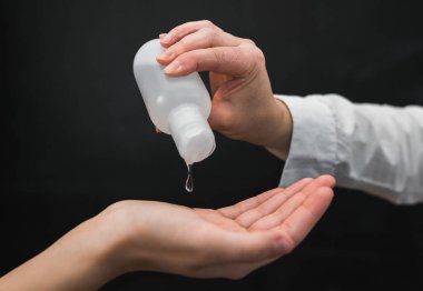 Ellerini alkol jeliyle ya da antibakteriyel sabunla yıkamak. Dezenfektan jeli. Doktor, hastasının ellerine alkol dezenfektanı döküyor. Coronavirus cihazları. Sağlık hizmetleri. Ellerini yıka..