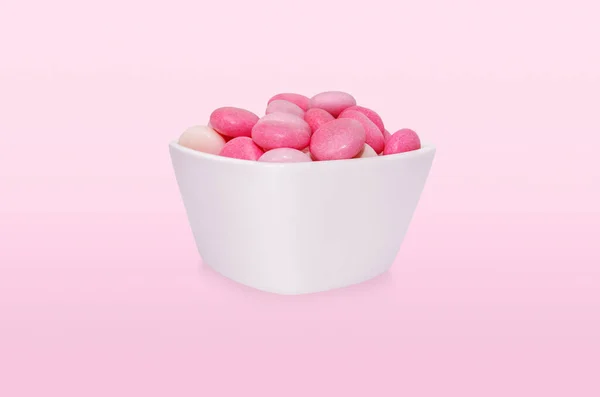 Group pink drops candies in bowl isolated on pink background