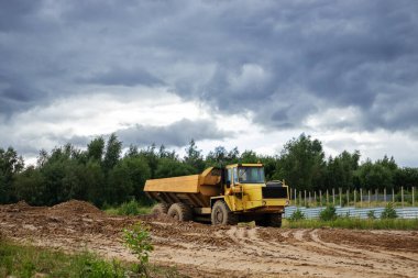 Döküntülü inşaat alanı, kamyon, ağaç, bulutlu gökyüzü