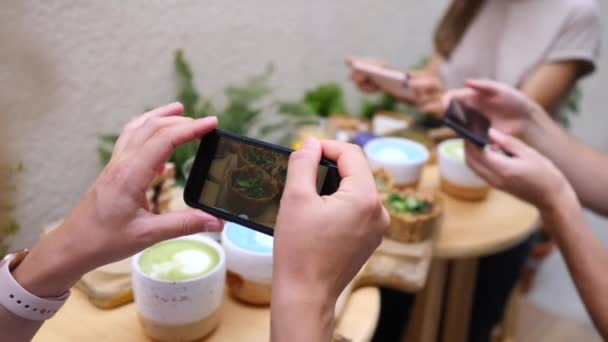 Друзі фотографії їжі з мобільних телефонів під час їжі разом . — стокове відео