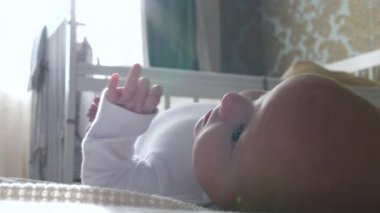 Küçük bebek gün ışığında yatağında yatıyor..