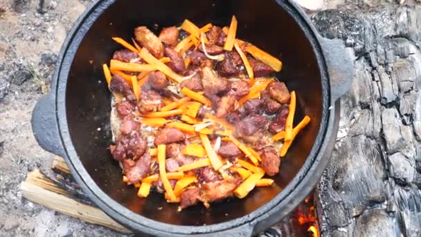 Příprava jídla na táboření. Smažené maso se zeleninou v ohni. — Stock video