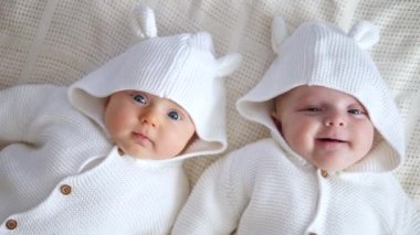 İki güzel bebek örülmüş kazaklarla yatakta yan yana yatıyor..