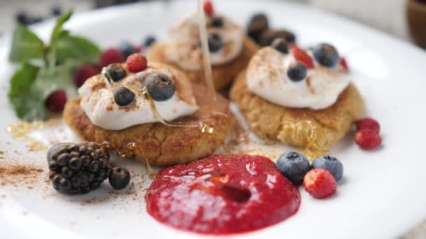 Versare il miele sulle frittelle di cagliata, i pancake Syrniki per colazione. Primo piano . — Video Stock