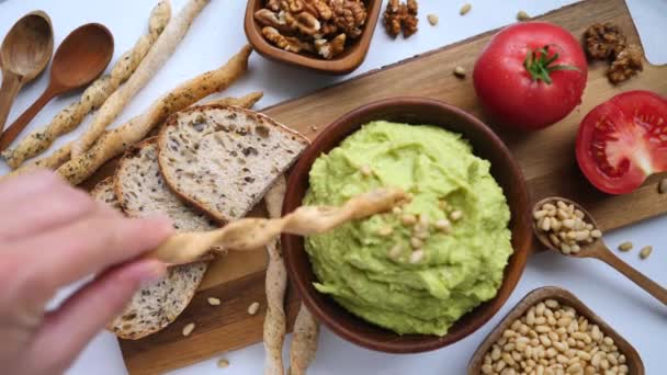 Mano femenina sumergiendo Grissini Breadstick italiano en salsa de aguacate Smash — Vídeos de Stock