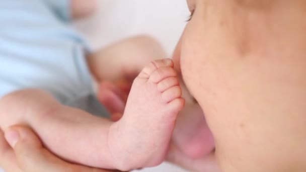 Молодая мама целует крошечные ножки своего ребенка. Крупный план . — стоковое видео