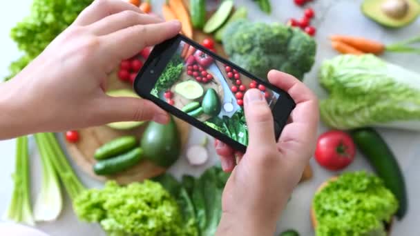 Mains de femme prenant des photos de nourriture végétalienne biologique fraîche à l'aide d'un smartphone . — Video