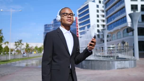 Dançando empresário usando Smartphone em fones de ouvido sem fio — Vídeo de Stock