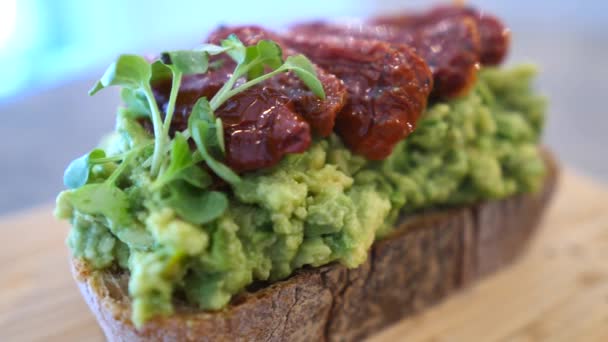 Veganský avokádový toast se sušenými rajčaty ke zdravé snídani. — Stock video