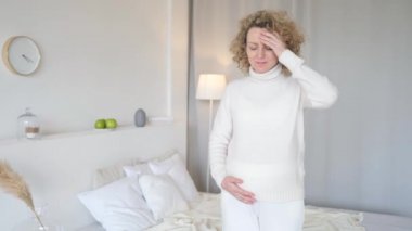 Evde baş ağrısı çeken hamile bir kadın.