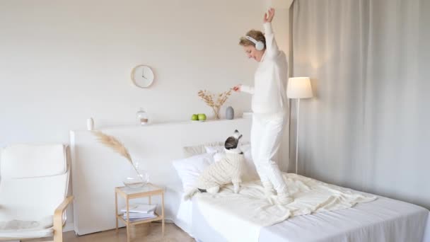 Gravid kvinna dansar och leker med hund hemma på sängen — Stockvideo