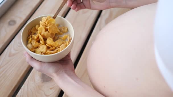 Schwangerschaft, gesunde Ernährung und Menschen-Konzept. Schwangere isst Cornflakes. — Stockvideo