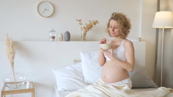 Gravid kvinna äter frukost i sängen. Begreppet graviditetsdiet. — Stockvideo