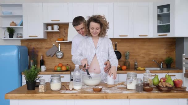 Glückliches schwangeres Paar bereitet gemeinsam in der Küche eine Mahlzeit zu. — Stockvideo