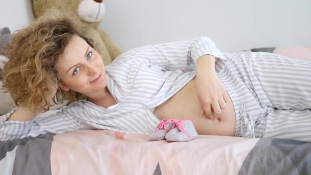 Ευτυχισμένη έγκυος γυναίκα ξαπλωμένη στο κρεβάτι. — Αρχείο Βίντεο