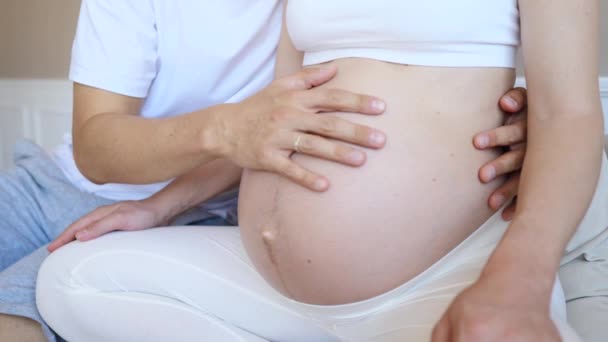 Мужчина трогает и ласкает живот своей беременной женщины — стоковое видео