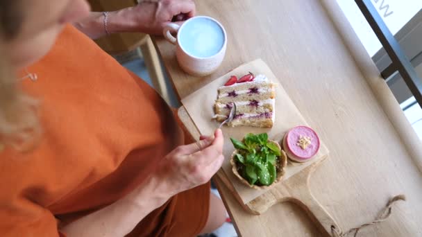 Gravid kvinna att äta frukost i Café äta veganska tårtor och dricka blått Matcha te. — Stockvideo