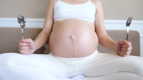 Hongerige zwangere vrouw wacht op diner met lepel en vork in handen. — Stockvideo