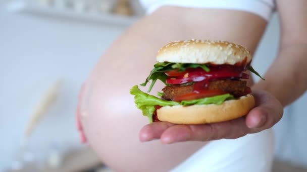 Здоровые альтернативы нездоровой пище. Беременная женщина держит веганский бургер . — стоковое видео