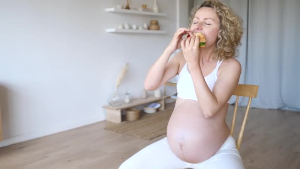 Zwangerschap hunkeren, Junk Food Concept. Hongerige zwangere vrouw eet hamburger. — Stockvideo