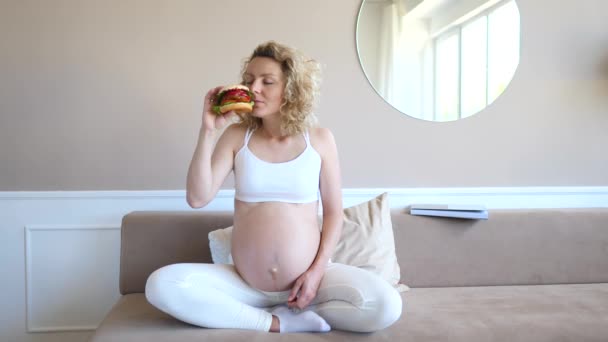 Fast Food hunkeren naar zwangere vrouw met hamburger. — Stockvideo