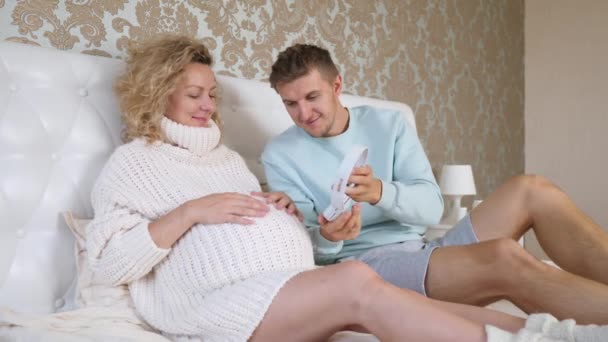 Toekomstige vader zet koptelefoon op zijn zwangere vrouwen buik. — Stockvideo