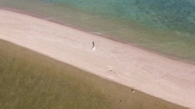 Cennet Adası 'ndaki kumsalda yürüyen genç bir kadın. Havadan Üst Çekim.
